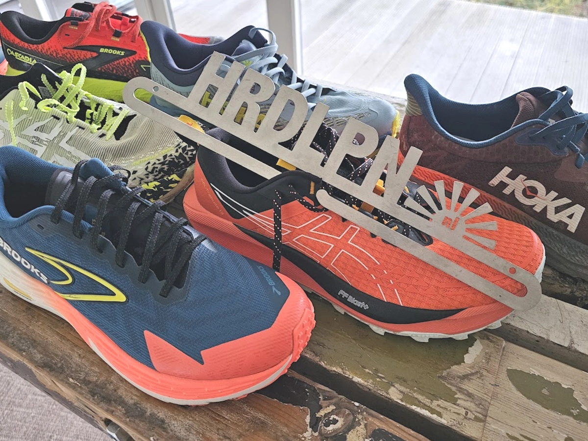 Trailrun schoenen naast elkaar zoals Brooks Catamount 4 Hoka Challenger 5 en Asics Metafuji Trail en Hoka Mafate 4